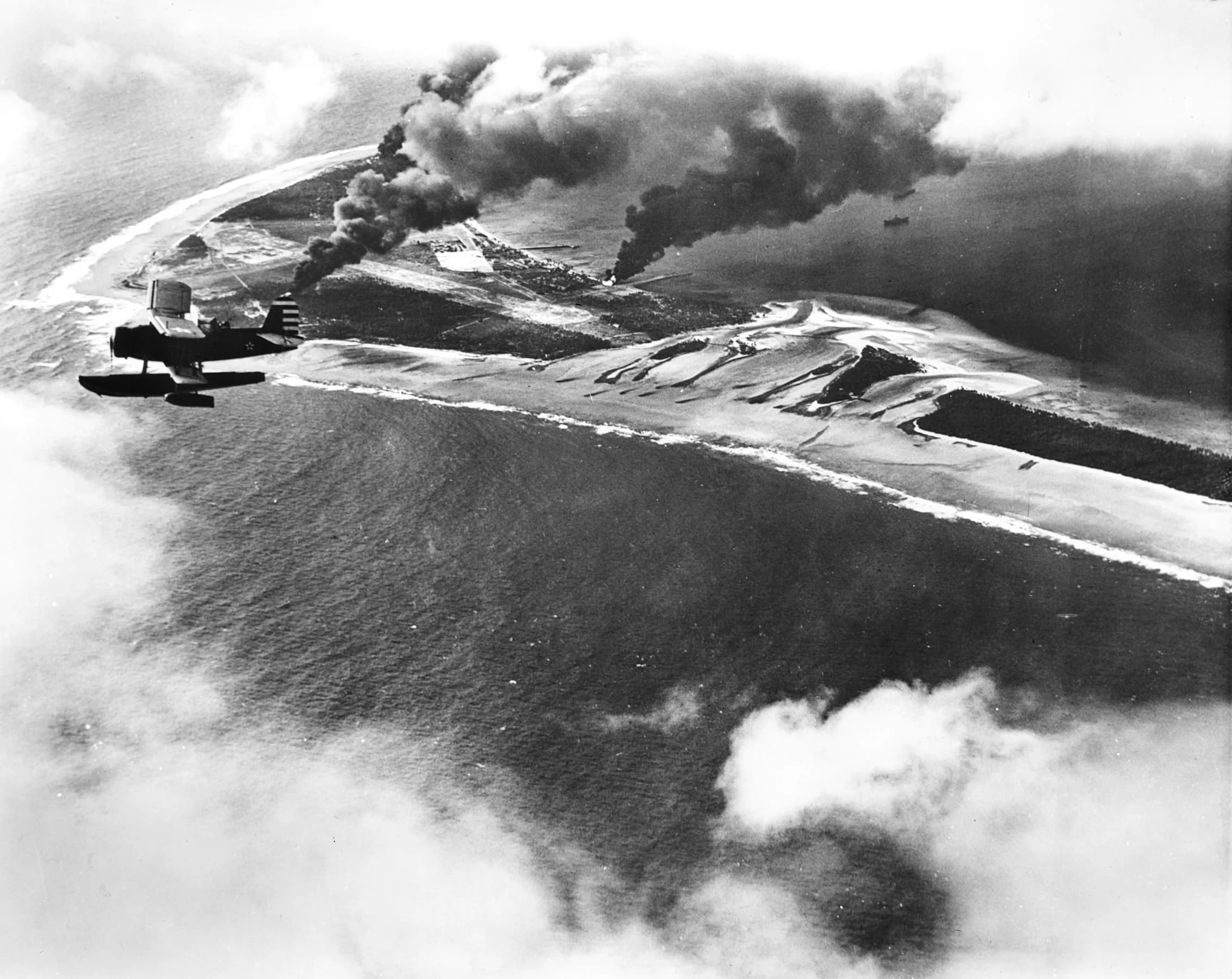 A U.S. Navy Curtiss SOC Seagull floatplane flies over Wotje Atoll, during the attack on the Japanese airfield there by gunfire from USS Salt Lake City (CA-25) and USS Northampton (CA-26) and fighters from USS Enterprise (CV-6), 1 February 1